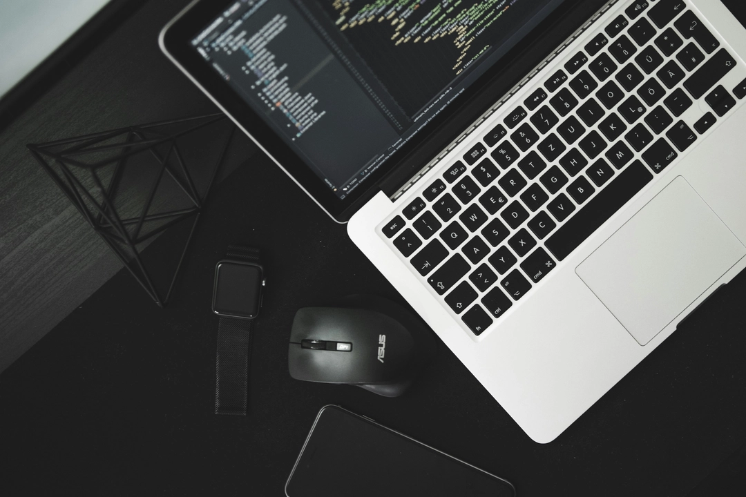 Modern workspace featuring a laptop displaying code, relevant to learning how to implement semantic versioning in software projects, alongside other tech gadgets like a smartwatch and smartphone.
