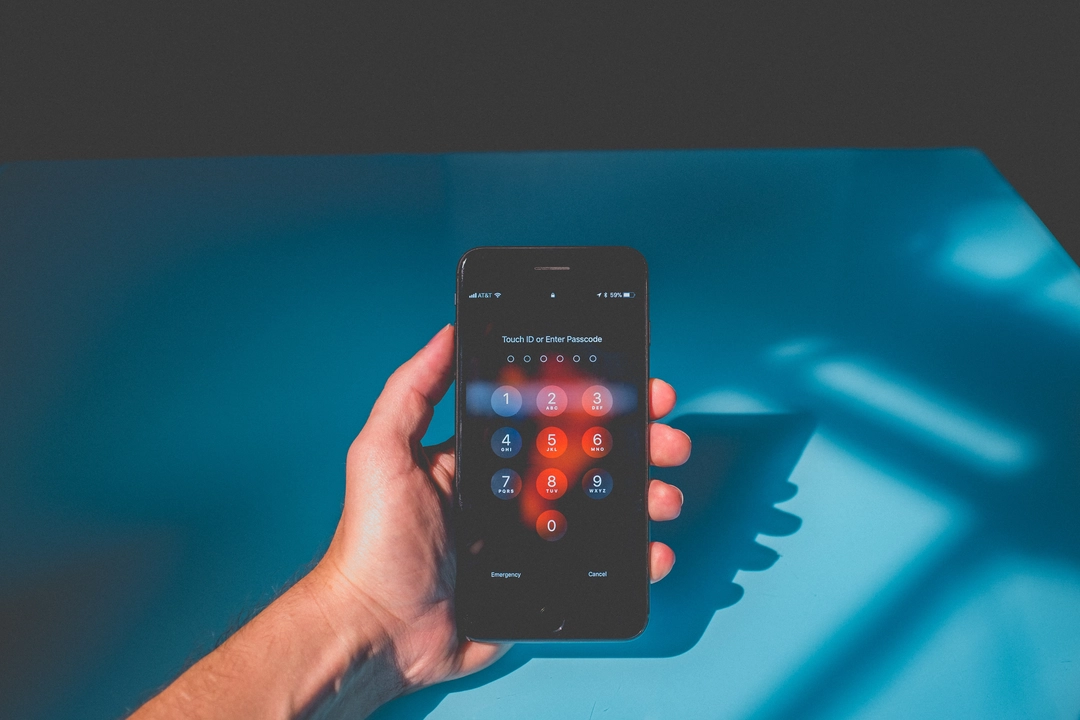 Hand holding a smartphone with passcode screen illuminated, demonstrating a secure password concept which can be created using a Python Click CLI Password Generator