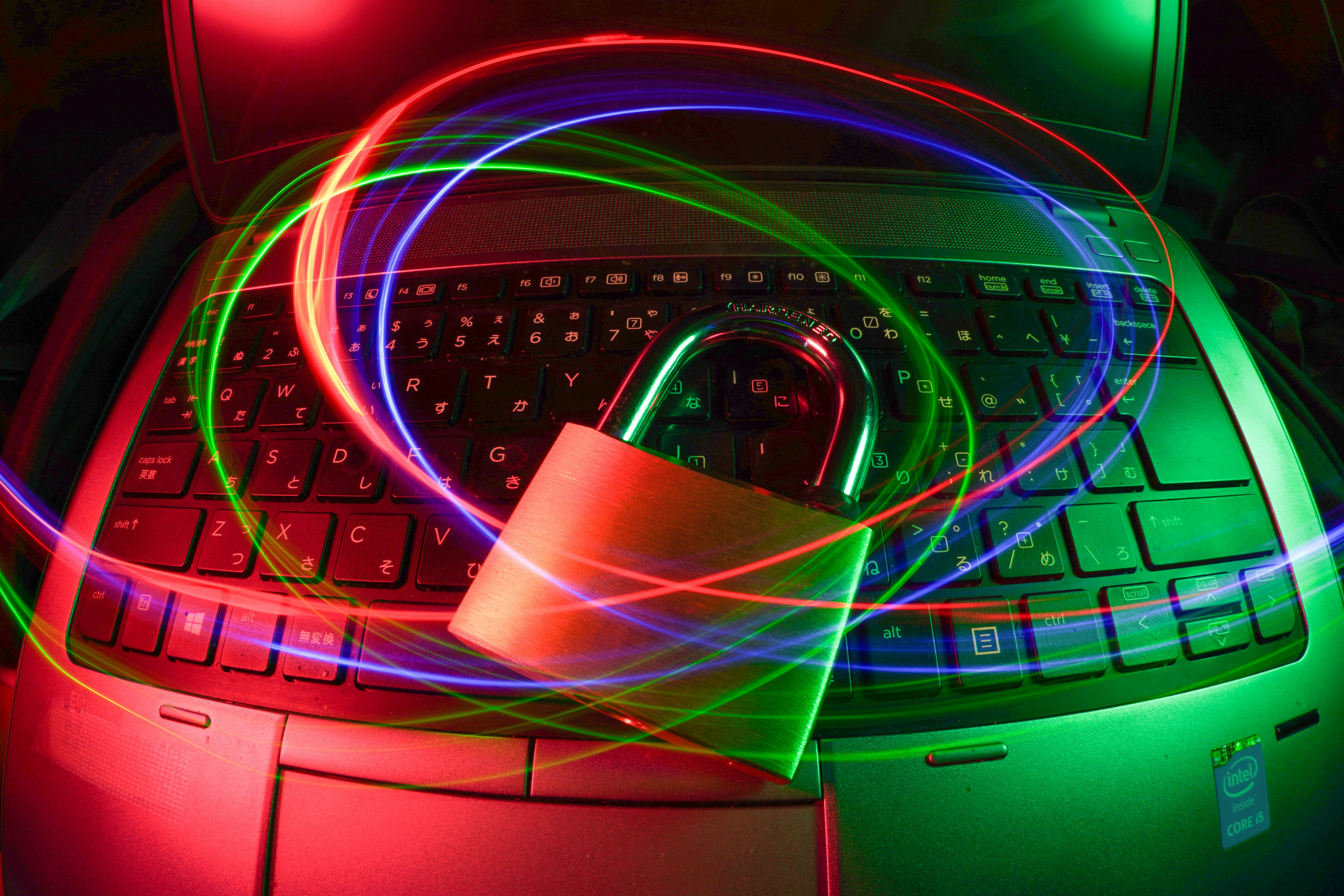 A padlock on a laptop keyboard with red and green light trails, symbolizing the secure implementation of the Principle of Least Privilege in software development.