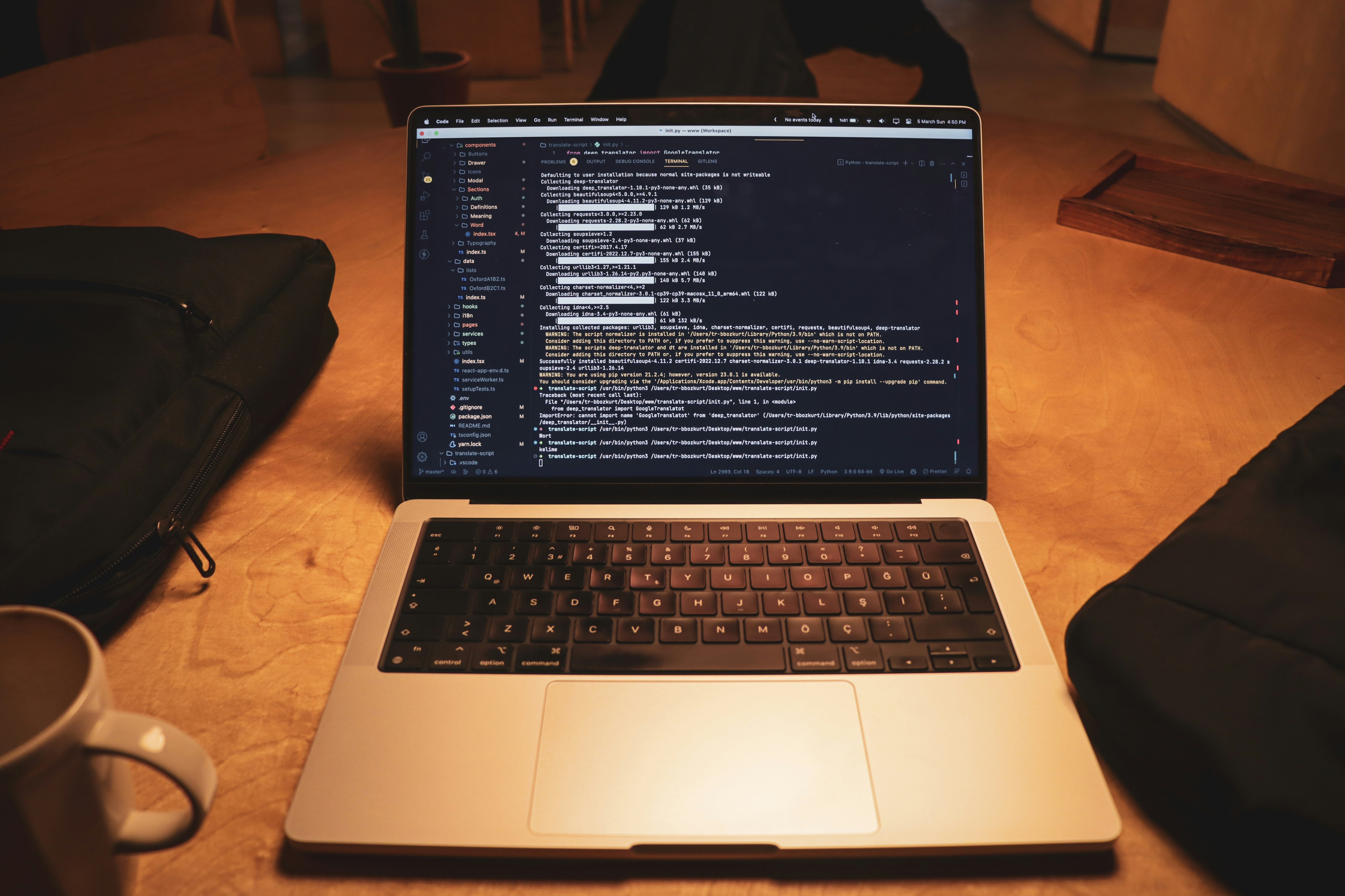A laptop displaying code using the Textual Python library for creating interactive terminal applications, set on a wooden desk with a cup of coffee and a backpack nearby.